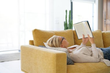 Orta yaşlı kadın evde kitap okuma