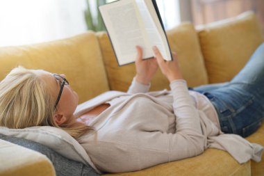 Orta yaşlı kadın evde kitap okuma