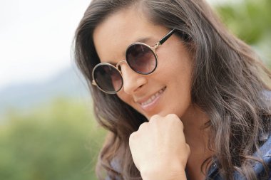 Güneş gözlüğü takıyor gülümseyen esmer kadın portresi