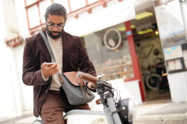 Hipster adam ile smartphone kullanarak elektrik vintage tarzı bisiklet