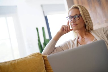 Sarışın kadın kanepe, rahatlatıcı bağlı dizüstü bilgisayar ile