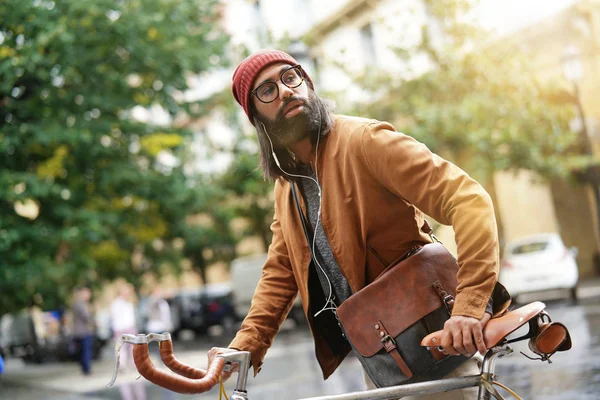 Hipster guy in town using earphones and fixie bike