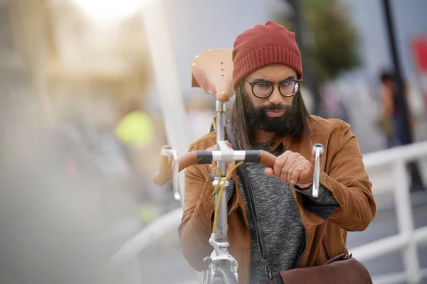 Hipster guy in town carrying fixie bicycle