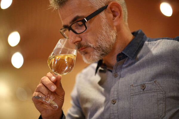 Winemaker tasting white wine in cellar