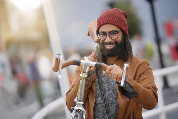 Hipster guy in town carrying fixie bicycle