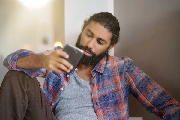 Hipster guy at home connected with smartphone