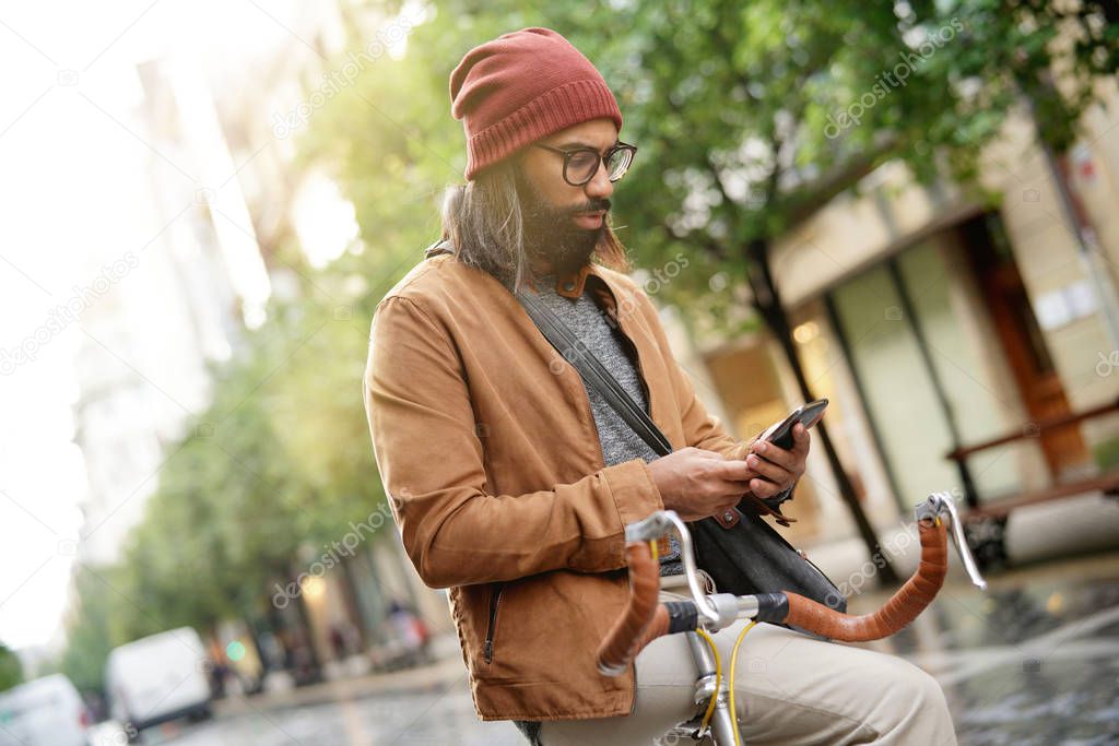 Portrait of hipster guy in the street connected with smartphone