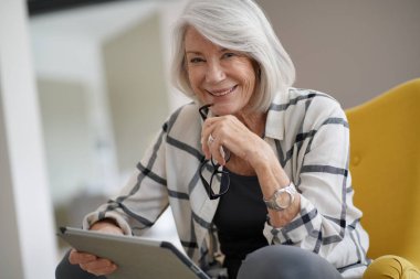 Evde tablet ile rahatlatıcı şık kadın kıdemli                               