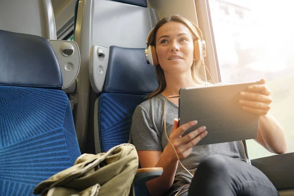 彼女のタブレットとヘッドフォンを電車で旅行する若い女性 — ストック写真