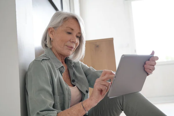 轻松的老年妇女坐在家里与平板电脑 — 图库照片