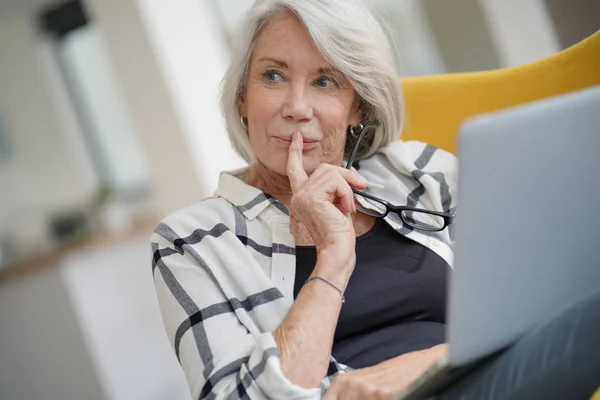 Relaxed modern senior woman at home on computer