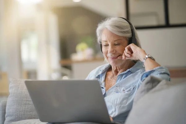 Senior Vrouw Thuis Laptop Met Hoofdtelefoon — Stockfoto