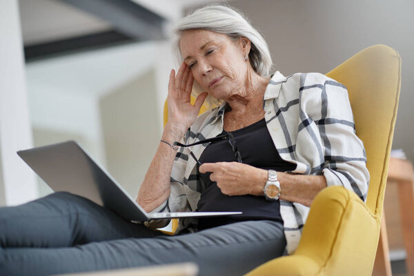 Modern senior woman thinking with computer                              