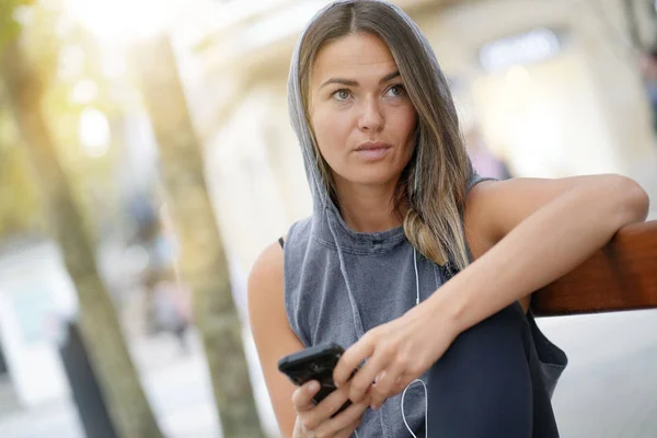 Young Woman Sitting Outdoors Holding Her Cellphone Thinking — Stock Photo, Image
