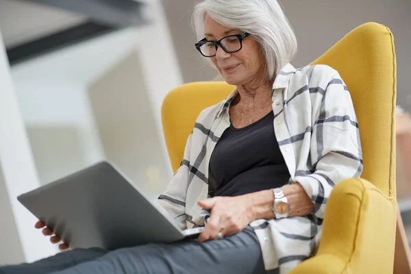Relaxed modern senior woman at home on computer
