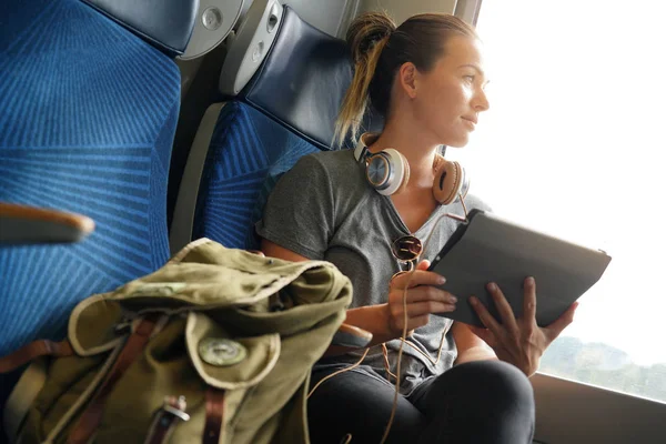 彼女のタブレットとヘッドフォンを電車で旅行する若い女性 — ストック写真