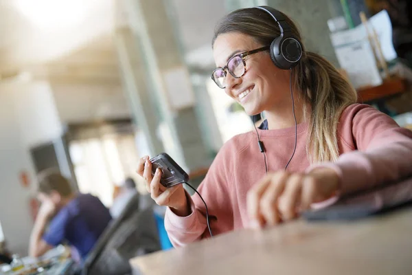 Young woman inside an urban space with headphones and devices