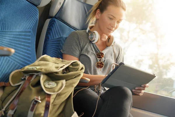 带着平板电脑和耳机乘火车旅行的年轻女子 — 图库照片
