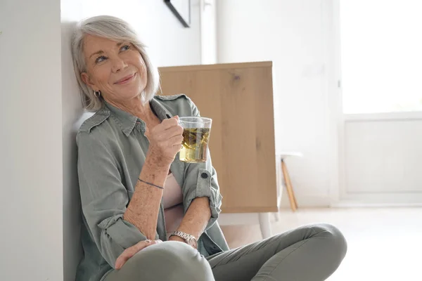 Attractive senior woman sitting on the floor at home