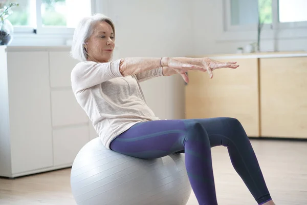 有吸引力的老年妇女在家里锻炼与瑞士球 — 图库照片