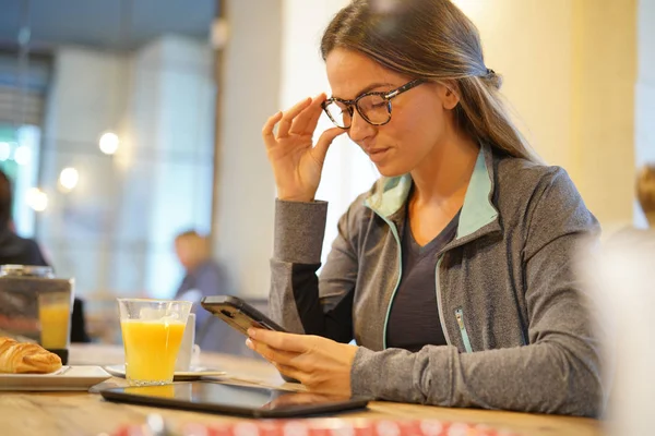 Egy Younf Egy Kávézóban Kiigazításáról Szemüvegét Nézni Vele Cellphone — Stock Fotó