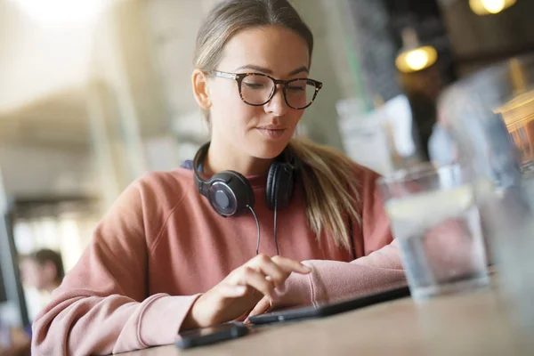 Young woman inside an urban space with headphones and devices