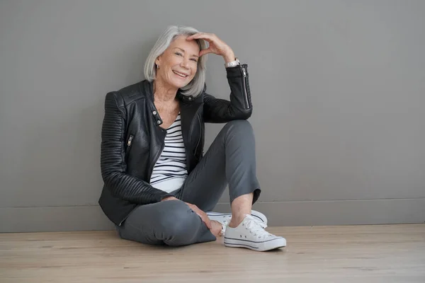 Moderne Senior Vrouw Zitten Binnenshuis Met Lederen Jas — Stockfoto