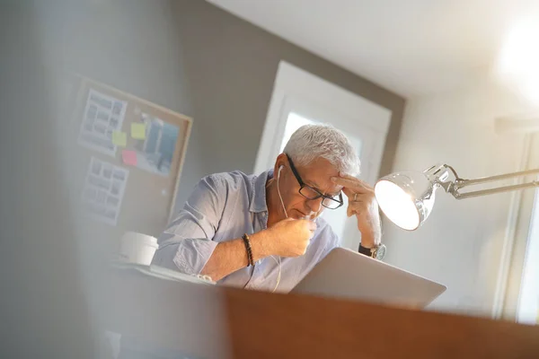 スマート フォンおよびイヤホーンを使用してオフィスでは 中年の男性 — ストック写真