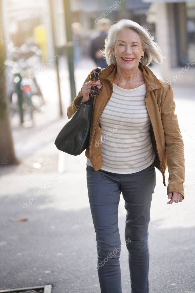  Attractive senior woman walking through town                              