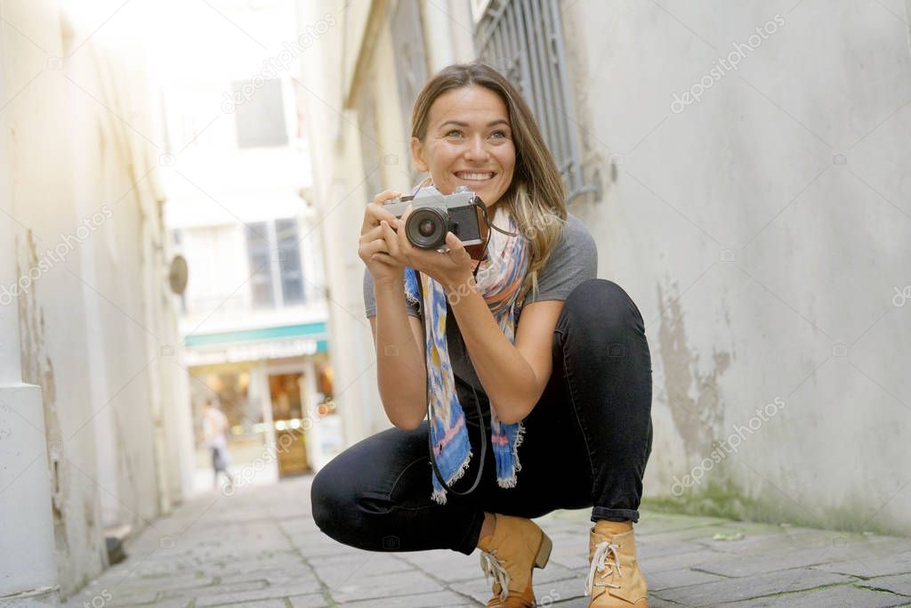 Young woman crouching donwn to take a photo with an SLR                         