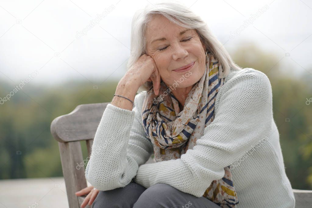 Beautiful senior womam sitting outdoors looking peaceful                                                       