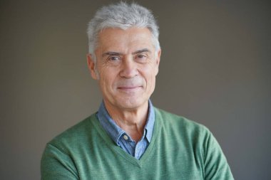 Portrait of modern smiling senior man on grey background                              