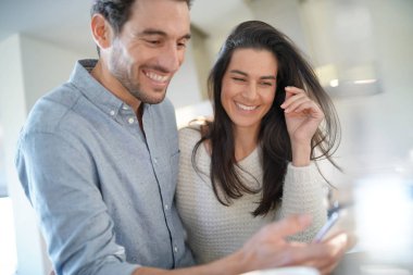  Çarpıcı çift cep telefonu mutfak mutlu bir şekilde bakarak                              