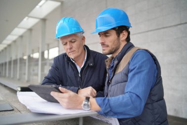 İşçiler modern yapı görüşü üzerine tabletle plan üzerinde danışmanlık yapıyorlar