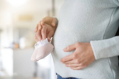 Göbek üzerinde istirahat bebek kız ayakkabıları ile bebek yumru yakın                             