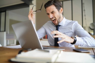 Sabır kaybetme ve modern ofis içinde laptop çığlık öfkeli işadamı
