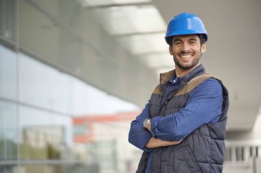 Modern binanın önünde hardhat gülümseyen sanayi işçisi  