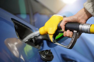   Close up of woman's hand pumping gas into car                              clipart