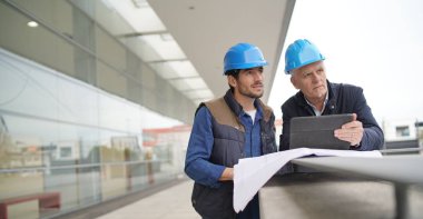 Modern bina görme planı üzerinde danışmanlık sert şapkalı işçi