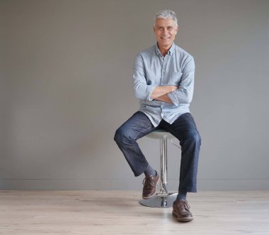  Full length casual senior man sitting on stool on gray background                               clipart