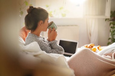 Laptop yatakta mutlu çekici genç kadın