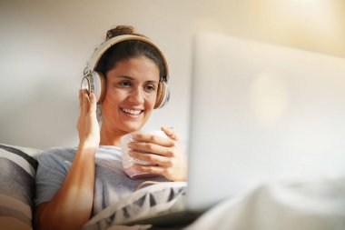 Ücretsiz esmer laptop ve kulaklık ile yatakta rahat makyaj