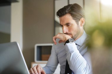 Yakışıklı işadamı modern ofis içinde laptop üzerinde çalışıyor 