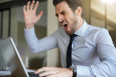Sabır kaybetme ve modern ofis içinde laptop çığlık öfkeli işadamı
