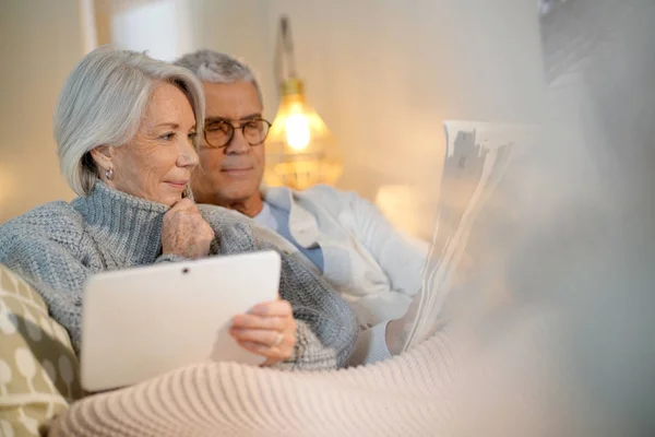 Coppia Anziani Che Rilassa Casa Sul Divano Con Tablet Giornale — Foto Stock