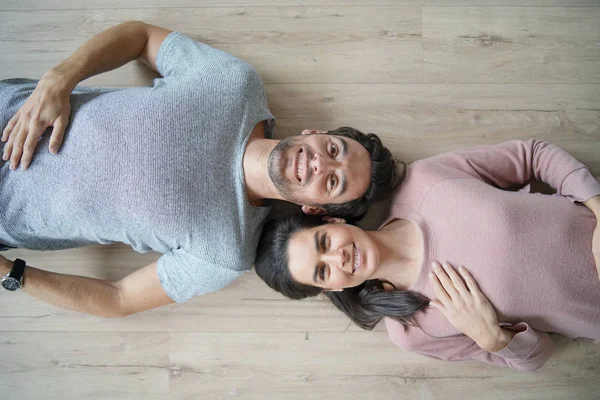 Glimlachend Paar Liggend Hardhouten Vloeren Camera Kijken — Stockfoto