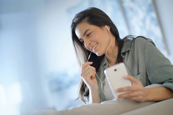 自宅のヘッドフォンと携帯電話で話している美しいブルネット — ストック写真