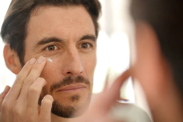 Schöner Mann Der Gesichtscreme Aufträgt Und Den Spiegel Schaut — Stockfoto