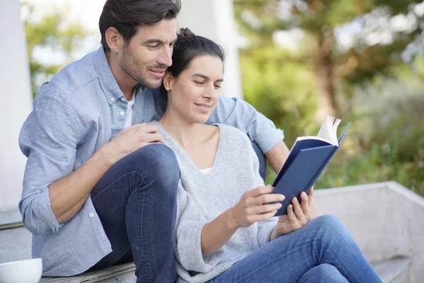 放松的年轻夫妇坐在外面看书 — 图库照片
