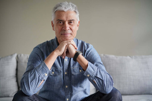  Portrait of casual modern senior man in denim on couch                              